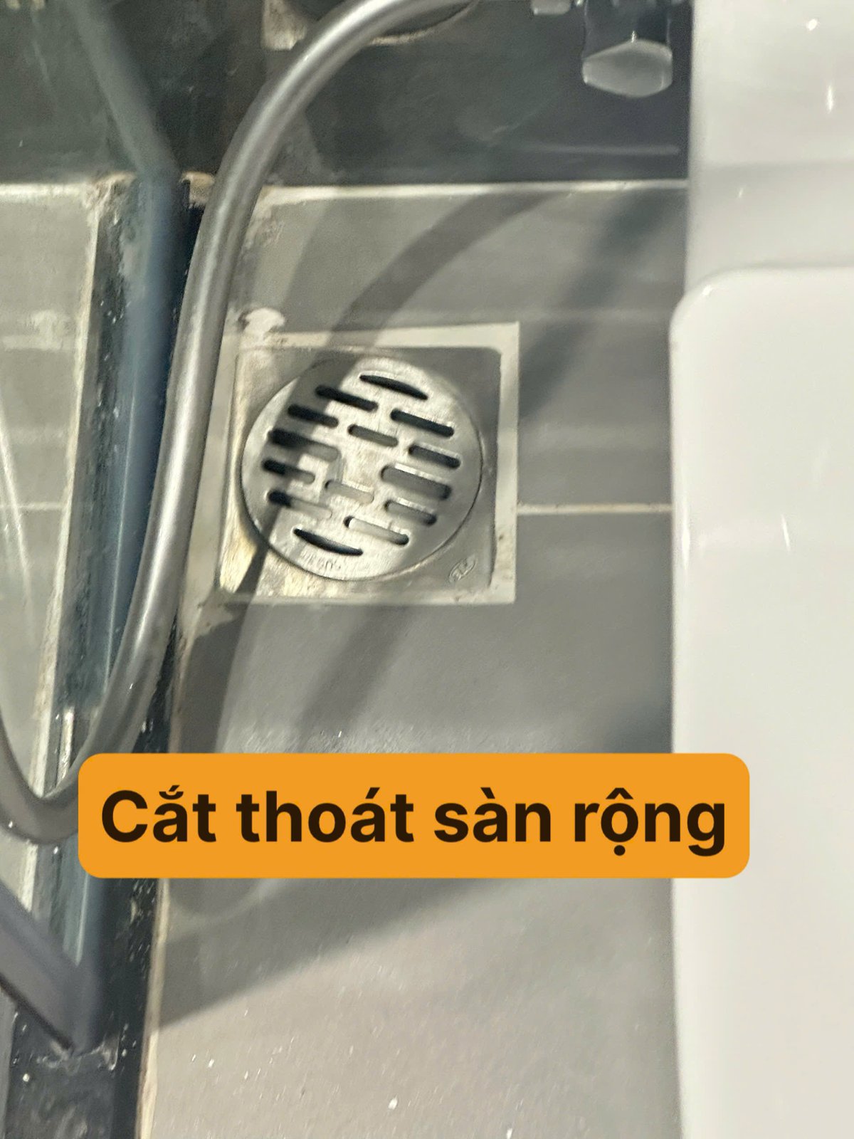 Phễu thoát sàn trong khu tắm có nhãn ghi lỗi "Cắt thoát sàn rộng" — vị trí cần xả nước thử và ghi vào danh mục tồn tại