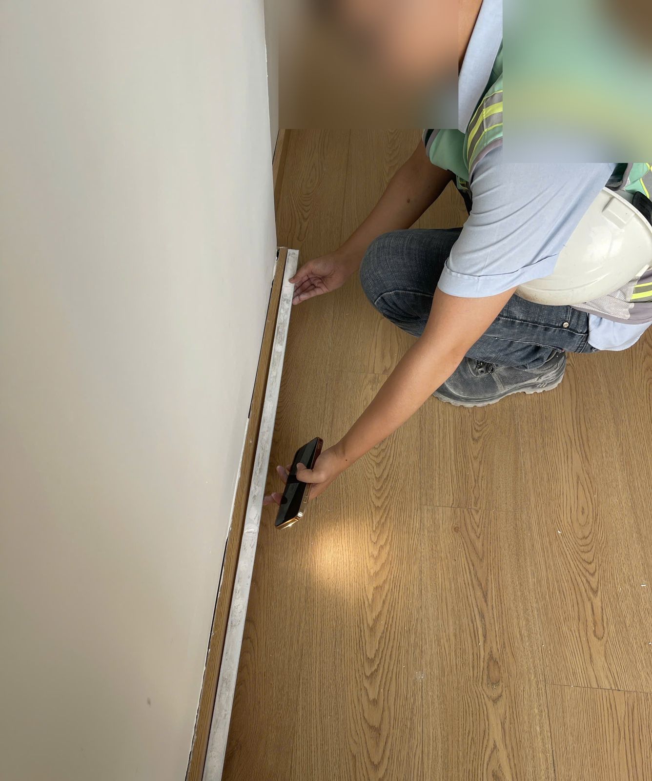 Người kiểm tra áp thước dài dọc chân tường và mặt sàn đã hoàn thiện
