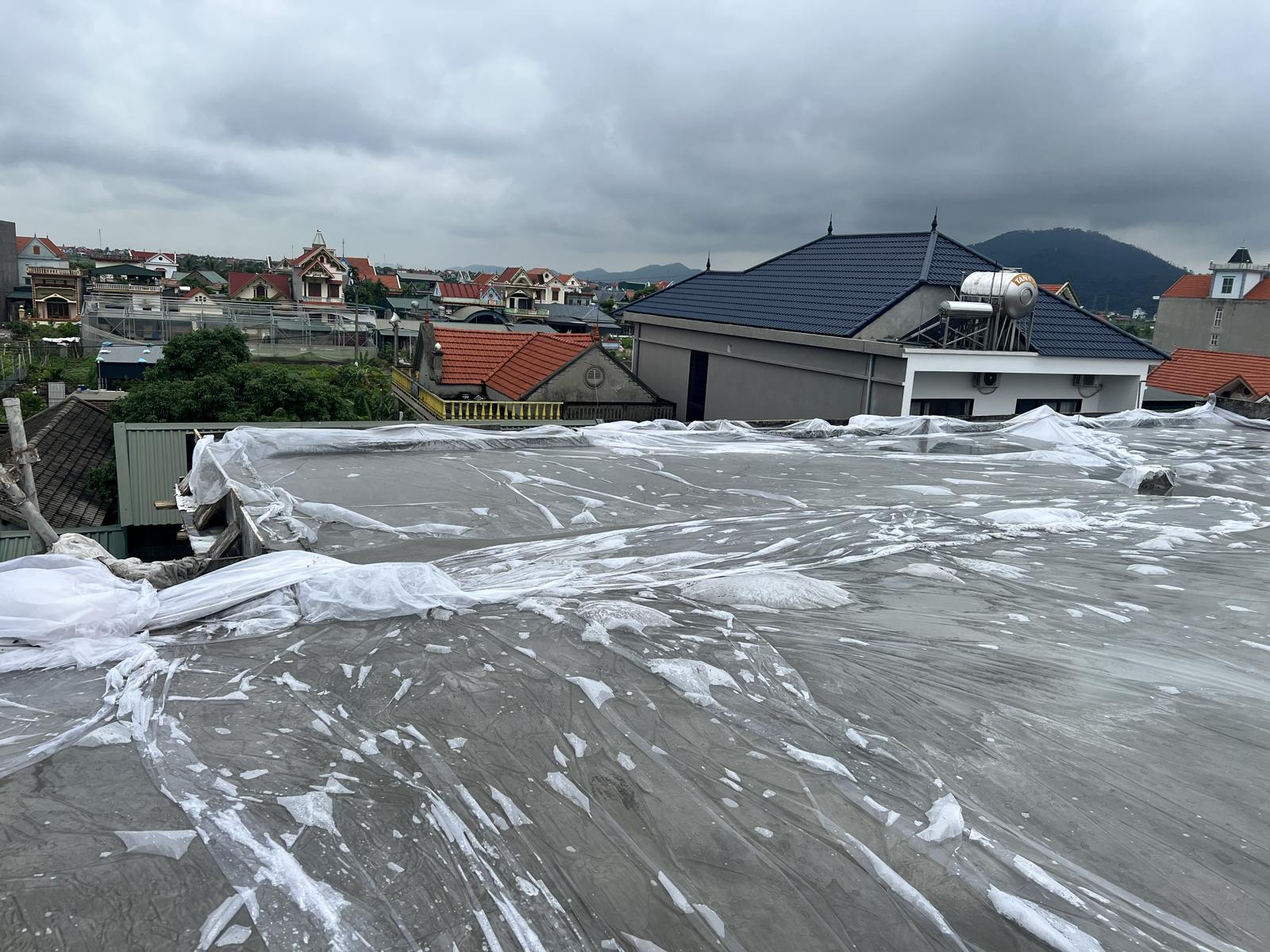 Sàn mái bê tông nhà dân được phủ kín màng nilon ngay sau khi đổ để giữ ẩm
