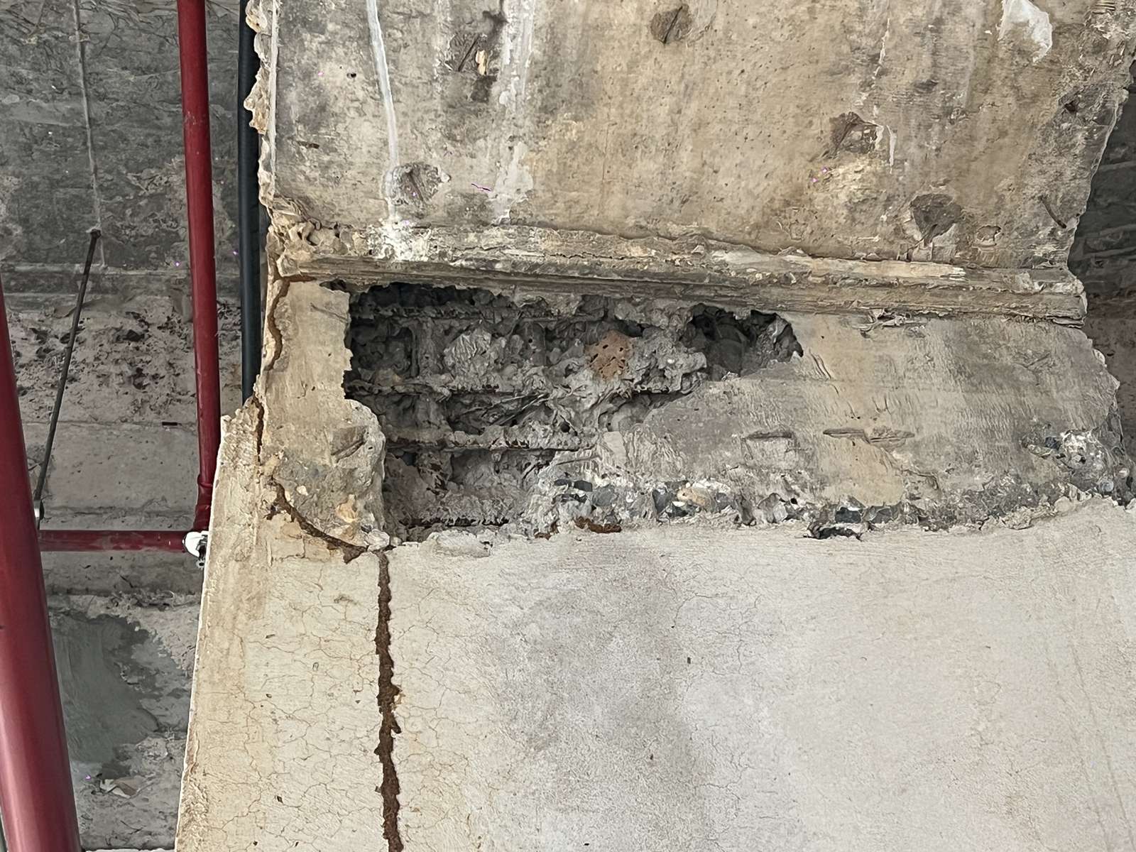 Mảng bê tông khuyết sâu ở vùng tiếp giáp giữa hai cấu kiện bê tông, nhìn thấy thanh thép bên trong và một vệt sẫm màu chạy dọc phía dưới