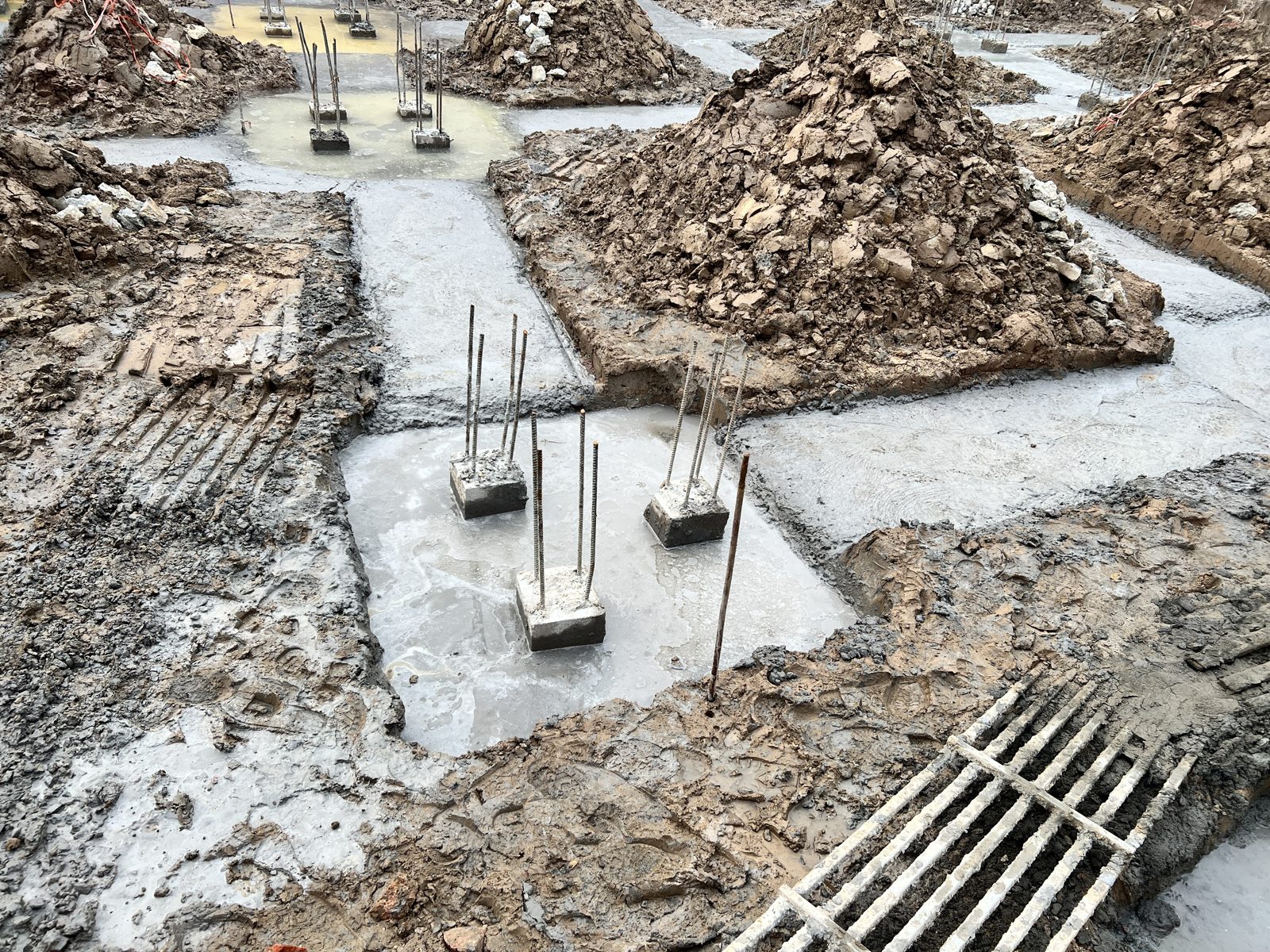 Hệ đài móng và giằng móng nhà dân đã đổ bê tông lót, thép chờ nhô lên ở các đài, các khung thép giằng đặt sẵn bên cạnh
