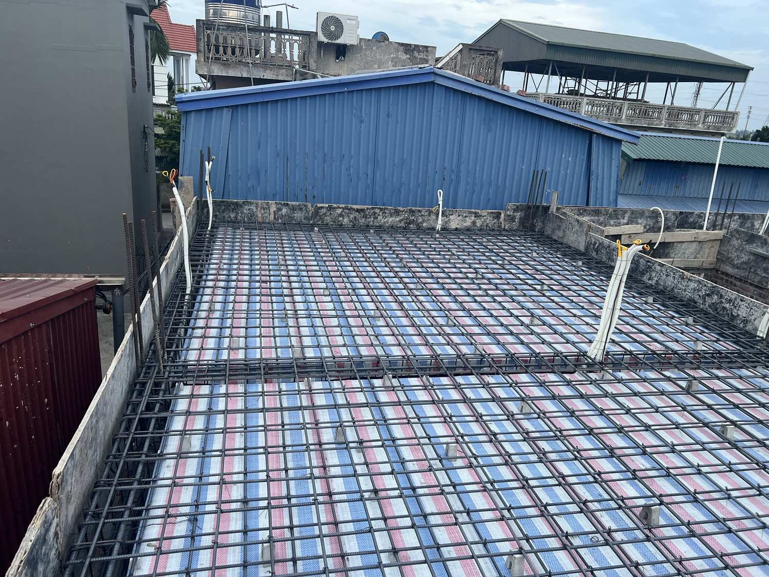 Lưới thép sàn hai lớp đã buộc xong cùng ống điện chờ trên mặt sàn nhà dân, trước khi đổ bê tông