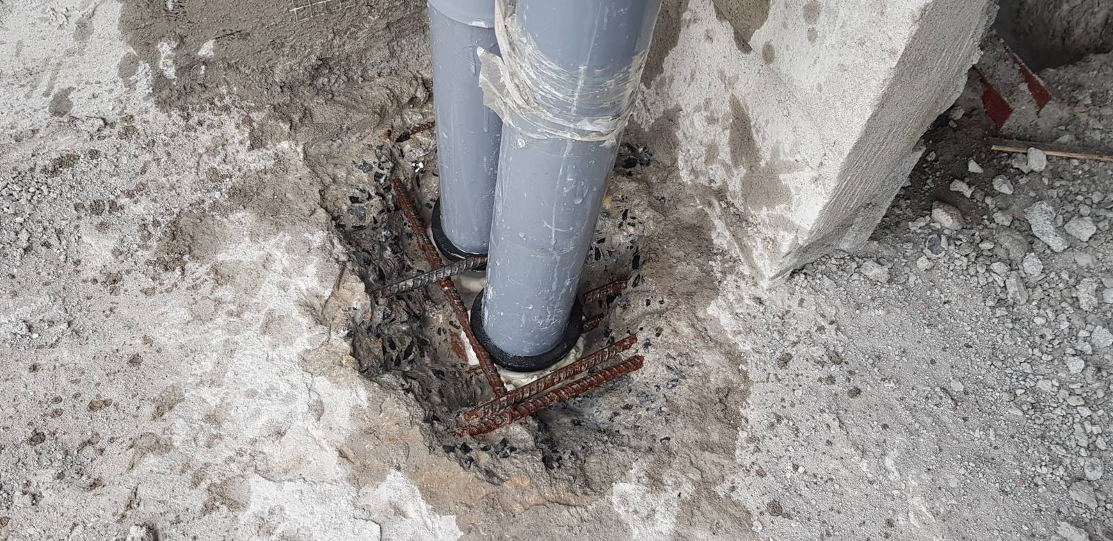 Cổ ống nhựa xuyên sàn bê tông đã được đục mở rộng, có thép gia cường bố trí quanh cổ ống trước khi chèn kín