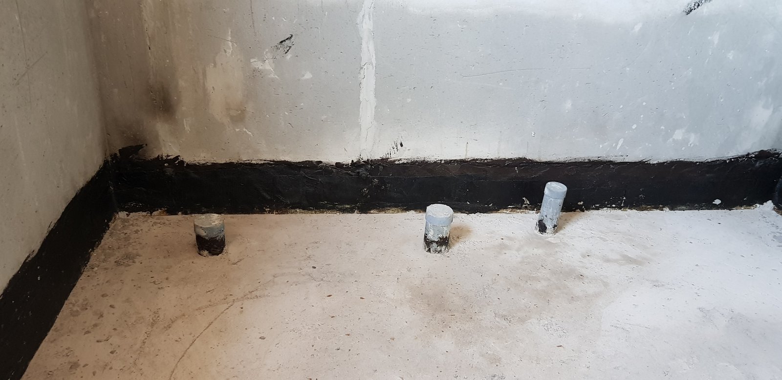 Lớp chống thấm quét phủ lên chân tường nhà vệ sinh, các cổ ống chờ nhô lên khỏi mặt sàn bê tông