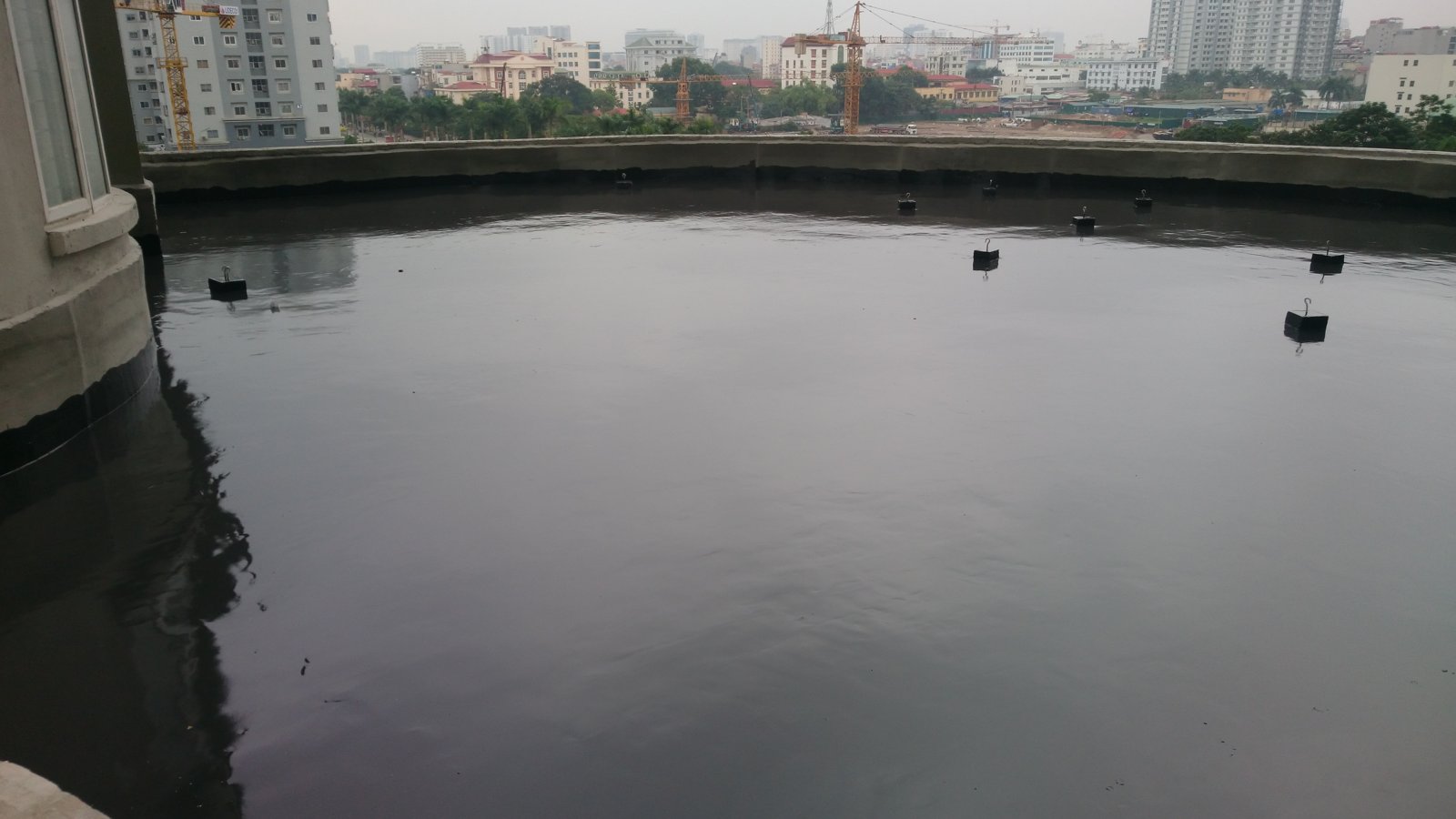 Mặt sàn đã thi công chống thấm đang được ngâm nước để nghiệm thu, mực nước phủ kín toàn bộ diện tích sàn