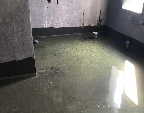 Sàn khu vệ sinh đang ngâm nước thử chống thấm, thấy rõ lớp chống thấm phủ chân tường và các cổ ống