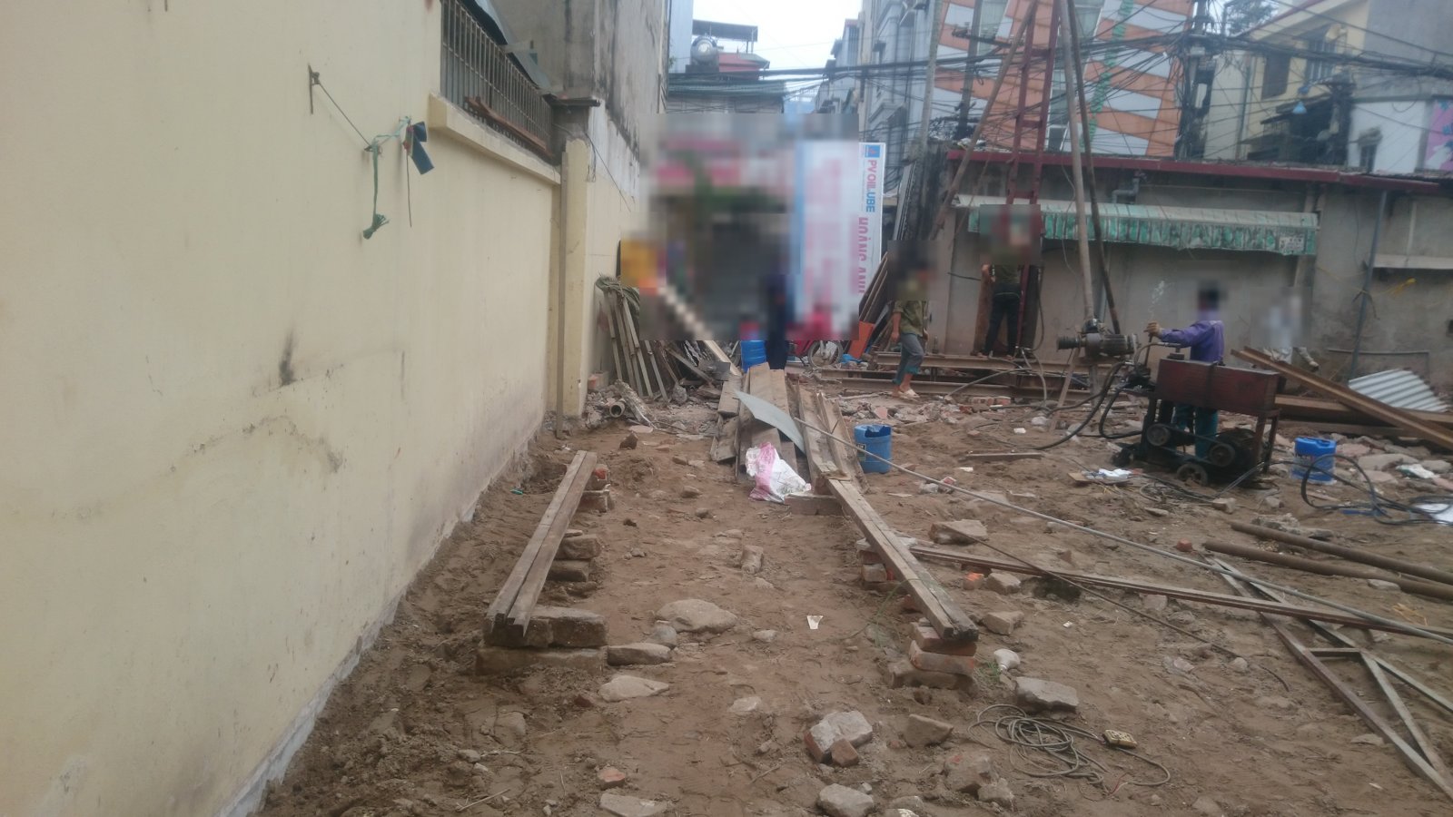 Dải đất hẹp chạy dọc bức tường dài của nhà bên cạnh, phía cuối mặt bằng là giàn ép cọc và máy móc đang tập kết