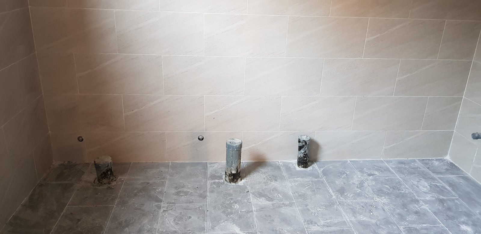 Nhà vệ sinh đã ốp lát xong nhưng chưa lắp thiết bị, còn trống mặt sàn để gõ kiểm tra gạch ốp lát bị bộp trước bàn giao