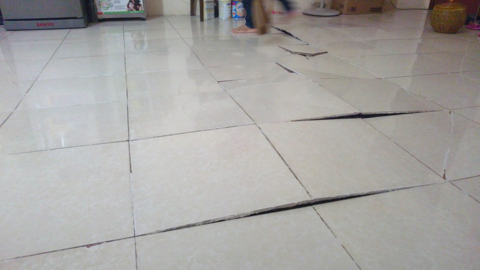 Mặt sàn gạch lát trong nhà đang ở bị bật mạch, mép viên cập kênh, dấu hiệu của lớp vữa lót không đầy
