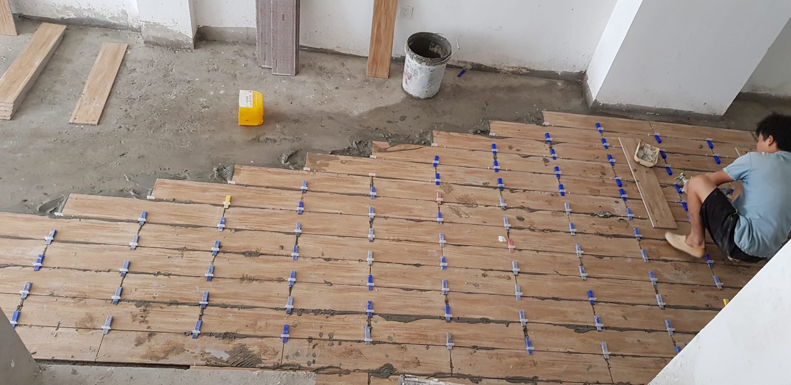 Thợ lát gạch giả gỗ, dùng ke chữ thập nhựa định mạch đều giữa các viên