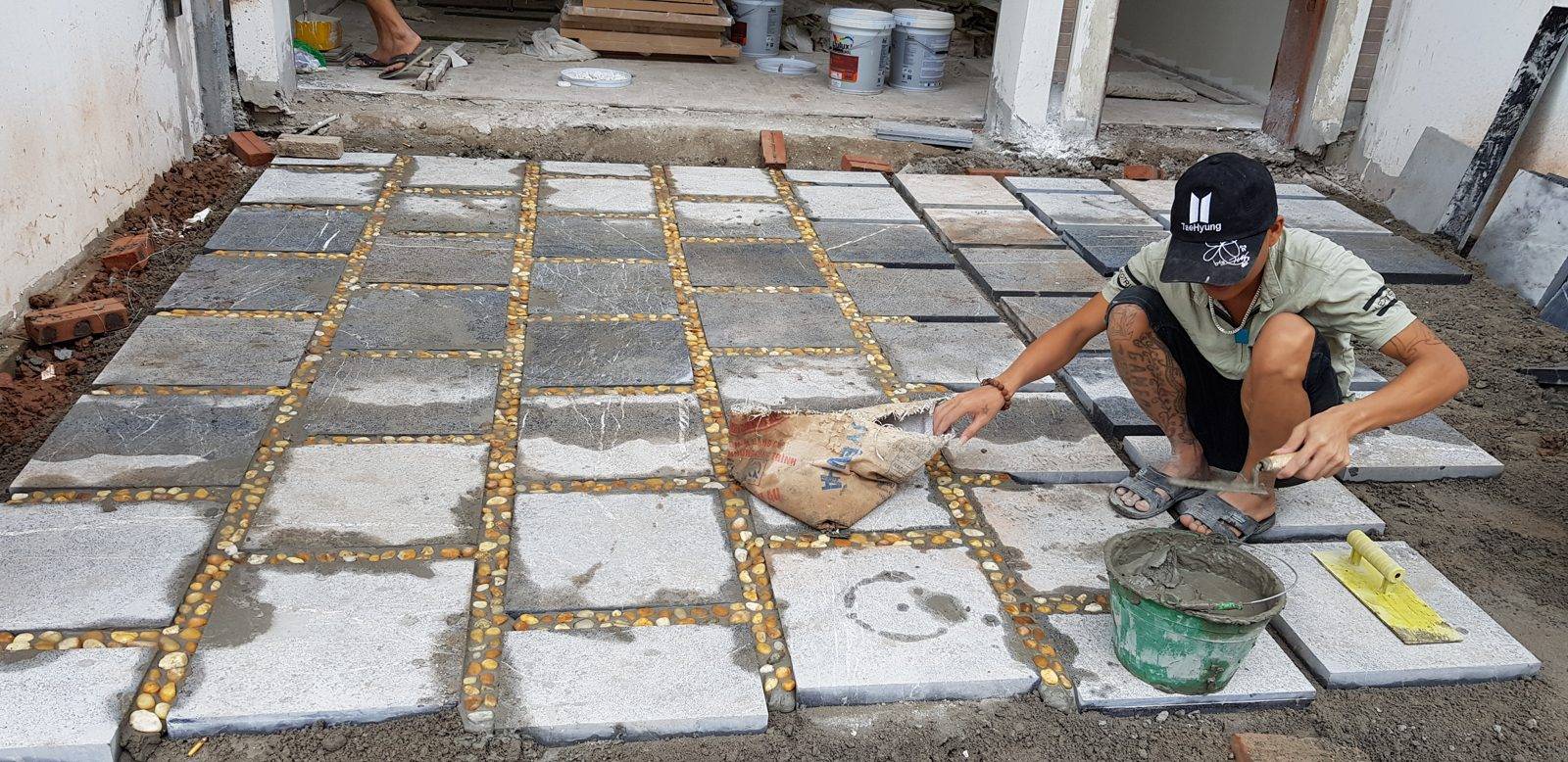 Thợ lát sân bằng đá, xử lý lớp vữa và mạch chèn sỏi giữa các viên lát