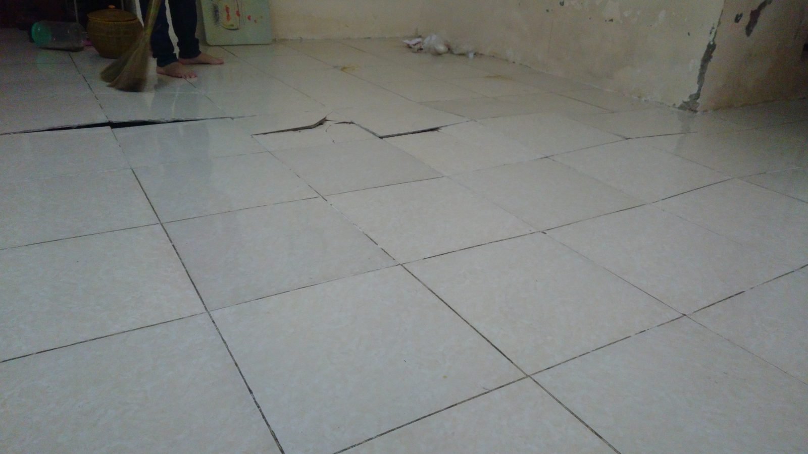 Viên gạch lát nền trong nhà đang ở đã bật hẳn lên khỏi lớp nền, khe hở lộ ra ở mạch