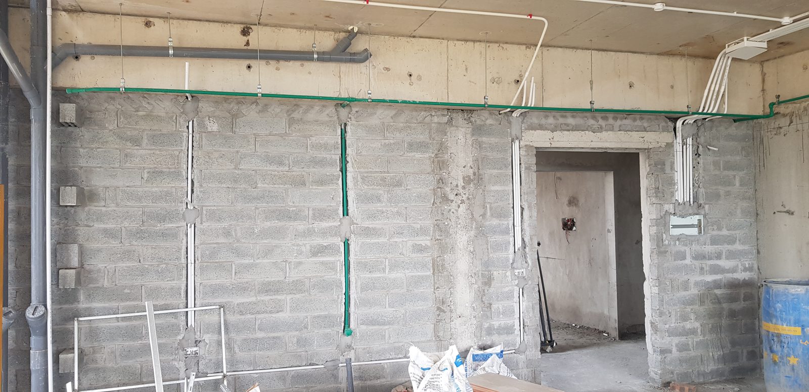 Tuyến ống điện và ống nước âm tường chạy thẳng đứng và nằm ngang trên mảng tường khối xây, đã chèn vữa