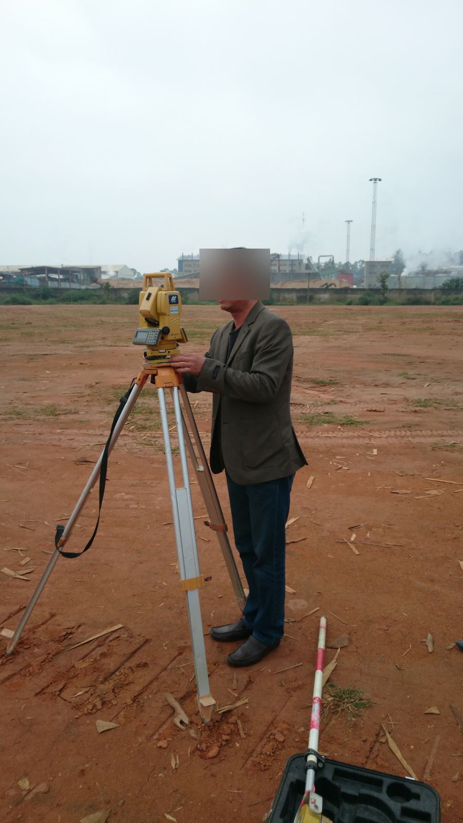 Kỹ sư dùng máy toàn đạc đặt trên chân ba càng để định vị tim trục và cắm mốc trước khi đào móng