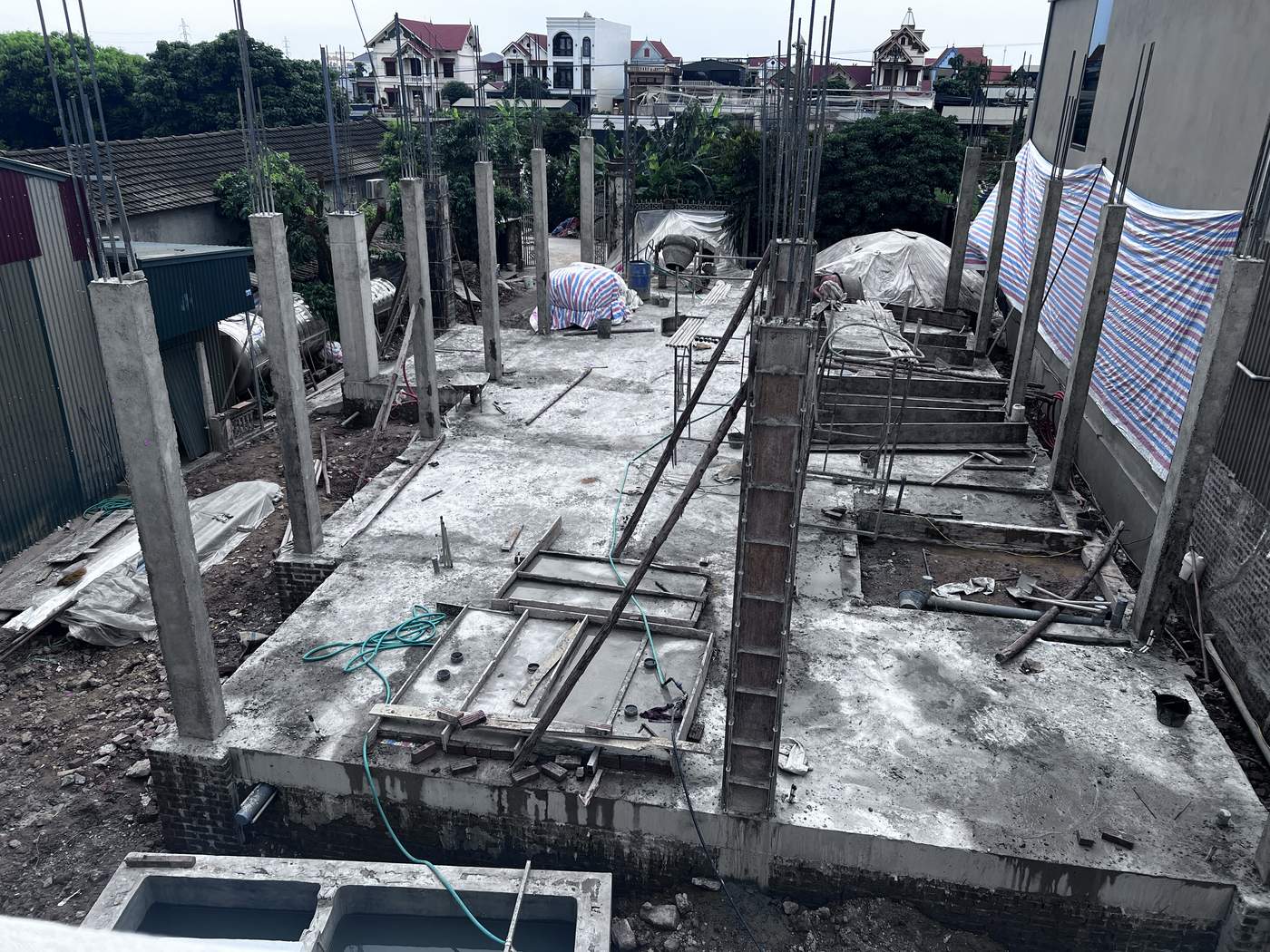 Công trường xây nhà dân với hệ cột bê tông đã đổ và cốp pha dầm sàn đang lắp dựng