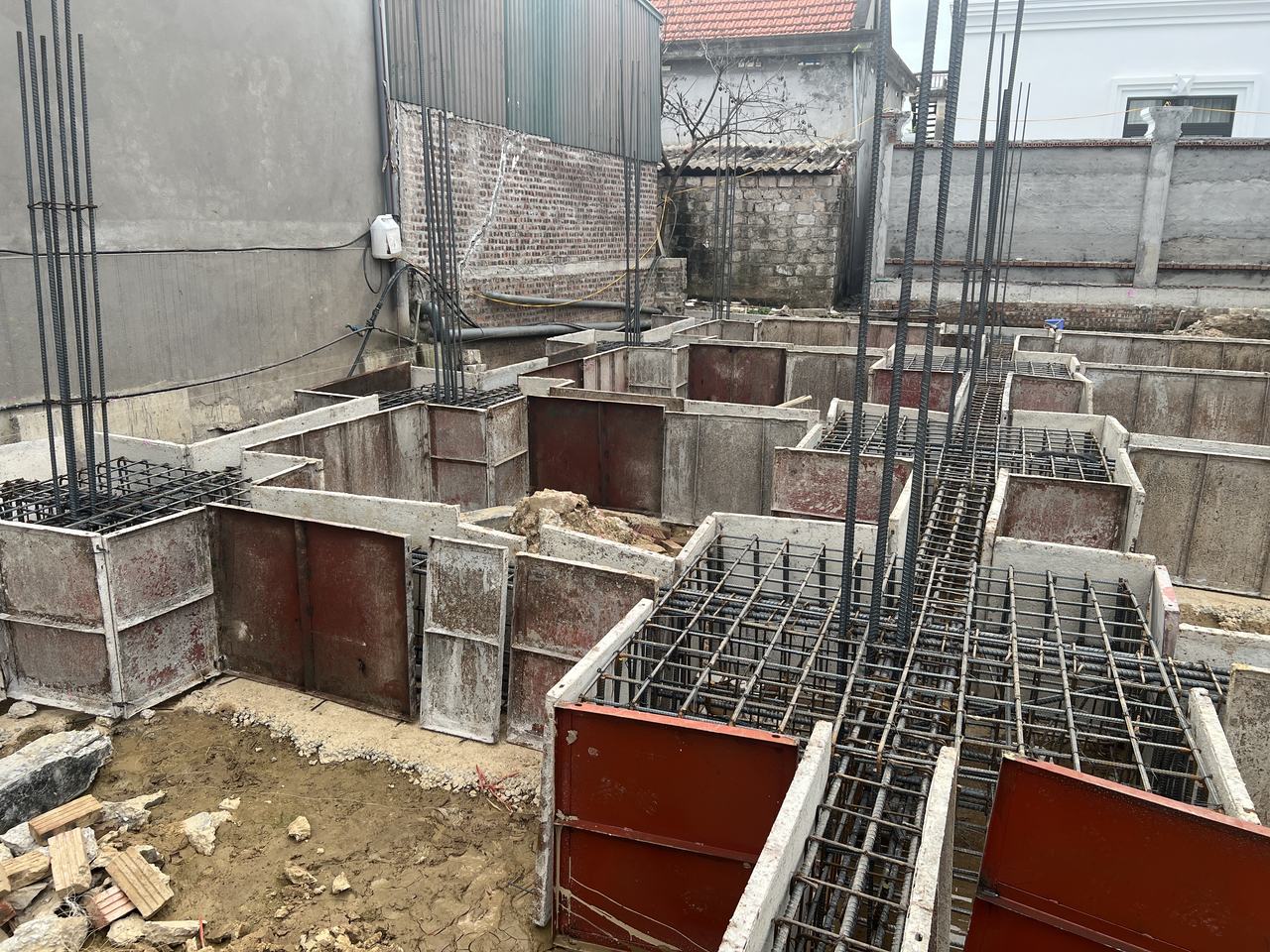 Đài móng có lưới thép và thép chờ cột dựng đứng, hai tuyến giằng móng nối vào hai phía, cốp pha thép đã ghép