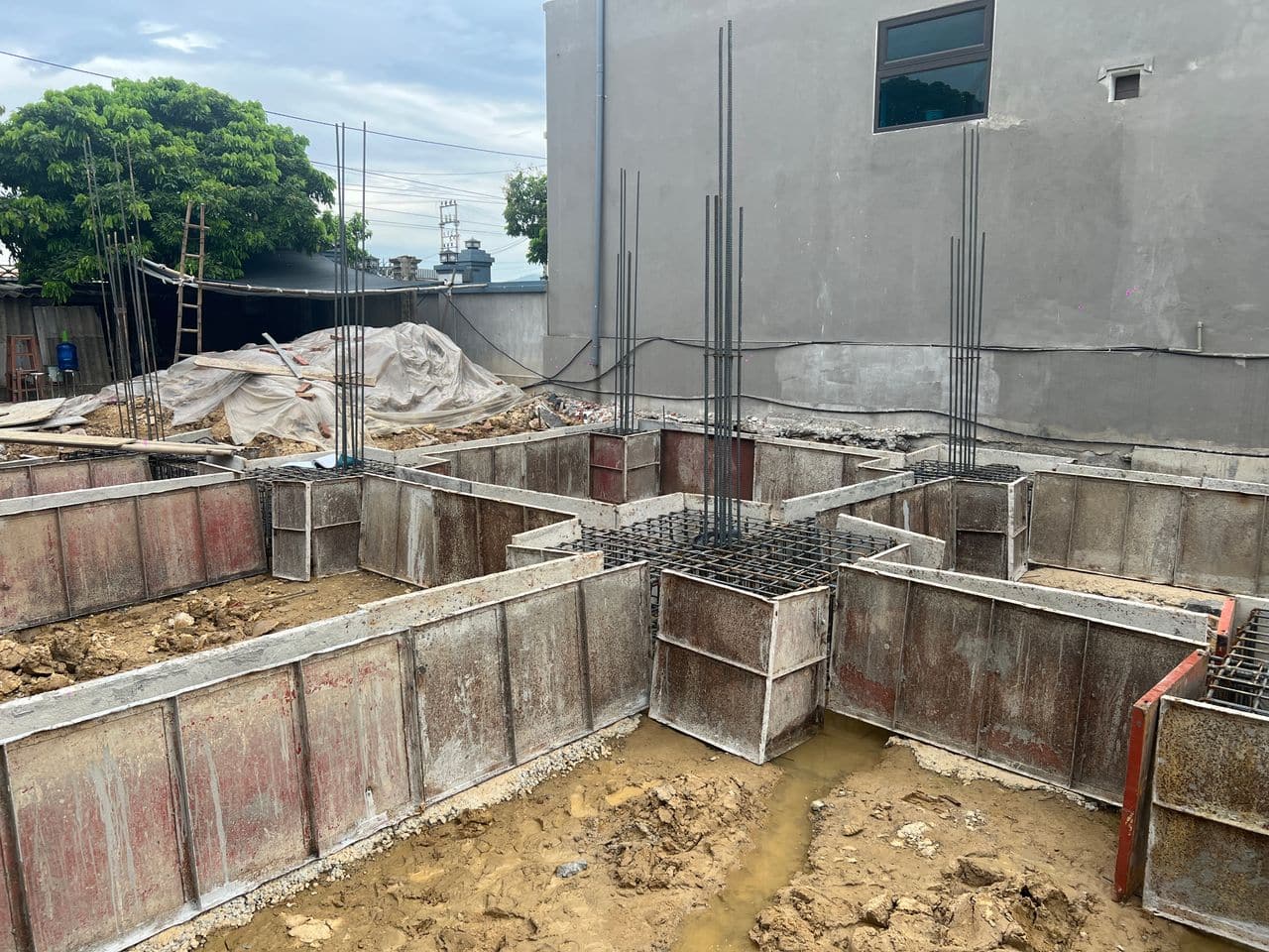 Thép chờ cột dựng thẳng đứng từ các đài cọc trong cốp pha thép, lưới thép đài và giằng móng nhìn thấy bên trong