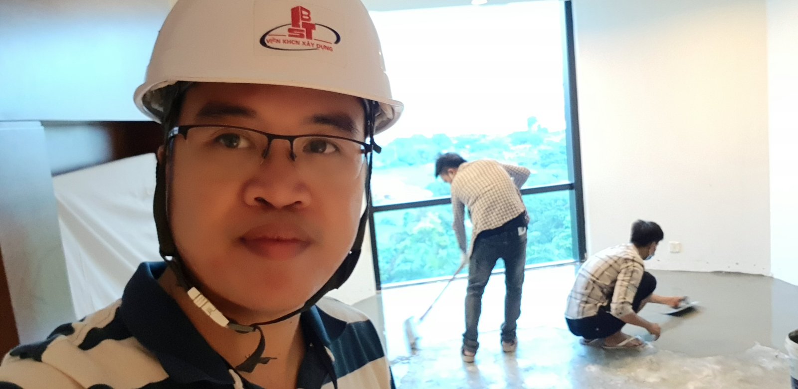 Kỹ sư giám sát đội mũ bảo hộ tại công trường trong lúc thợ đang thi công sàn