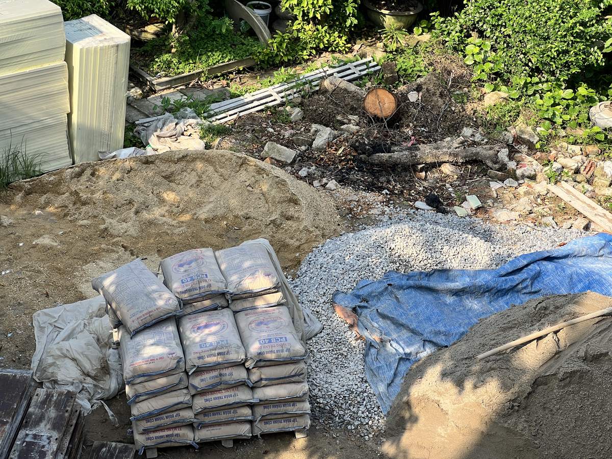 Xi măng kê trên pallet, cát và đá dăm tập kết tại công trường nhà dân