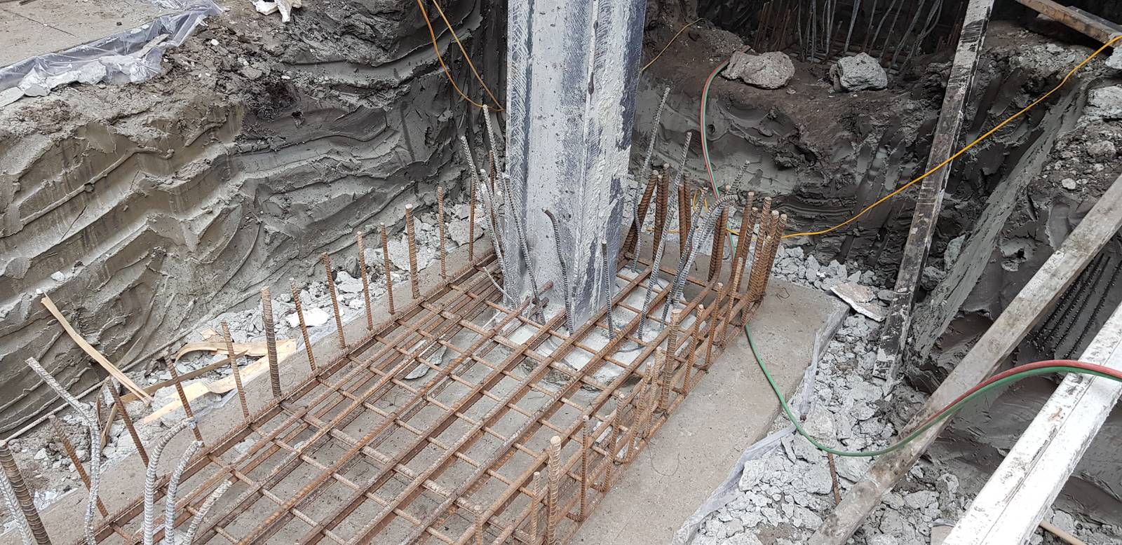 Cốt thép giằng móng đã buộc xong trên lớp bê tông lót trong hố móng, thép chờ cột nhô lên chờ nghiệm thu trước khi đổ bê tông