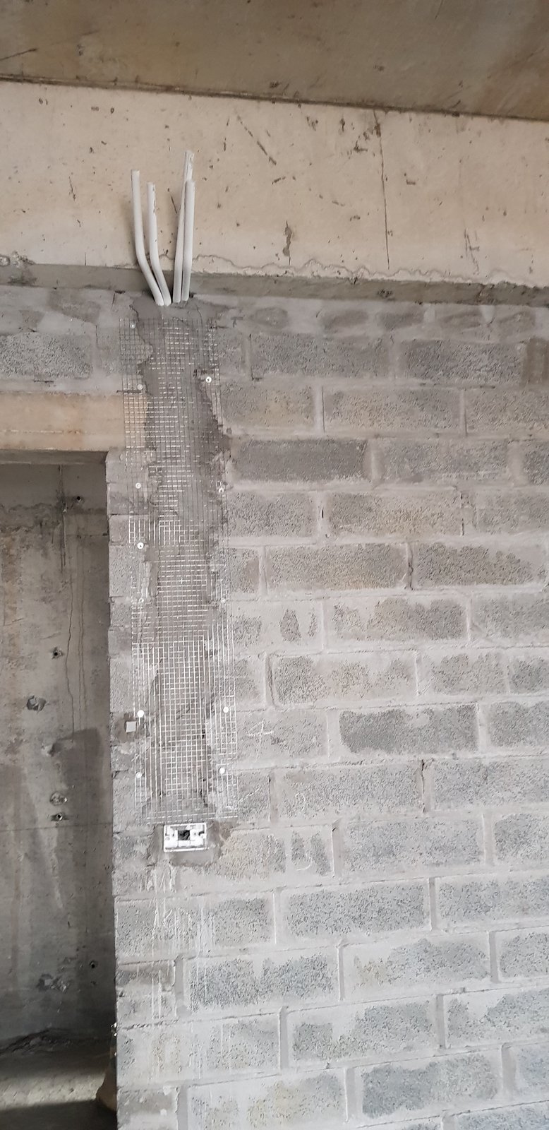 Rãnh điện âm tường chạy dọc từ dầm xuống đế âm, đã trát vá và phủ lưới thép chống nứt, ba ống điện chờ còn lộ ra ở đầu rãnh